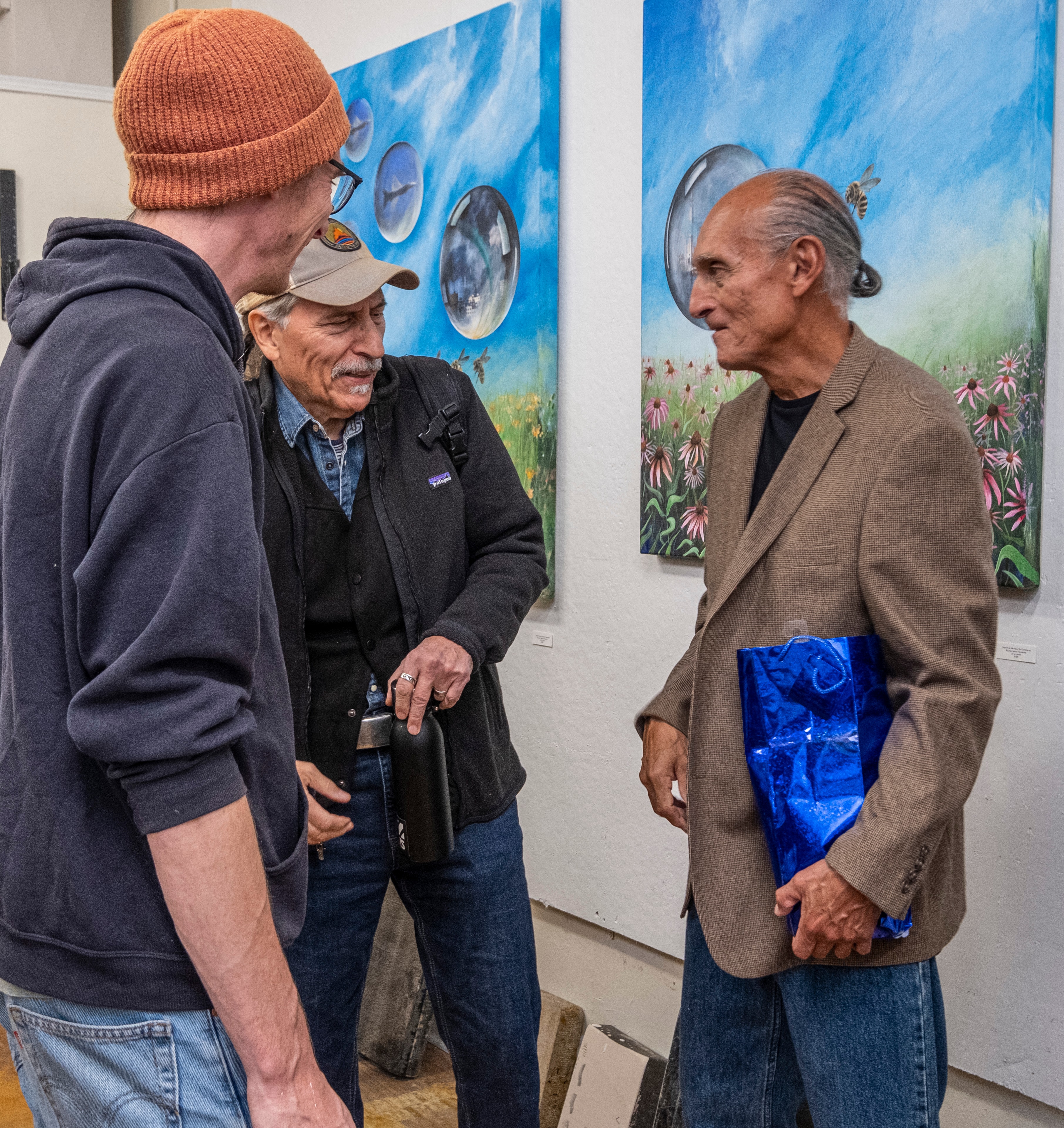 Echo of Resistance — Chicago poet Carlos Cumpian and Chicago artist and musician Francis in conversation at Ricardo's exhibition Echo of Resistance, Hoof Print Chicago. The Healing Plants paintings — spheres reflecting bees, wildflowers, and coneflowers — fill the gallery wall behind them. Photography by Fugi Almanza. by Ricardo Santos Hernández