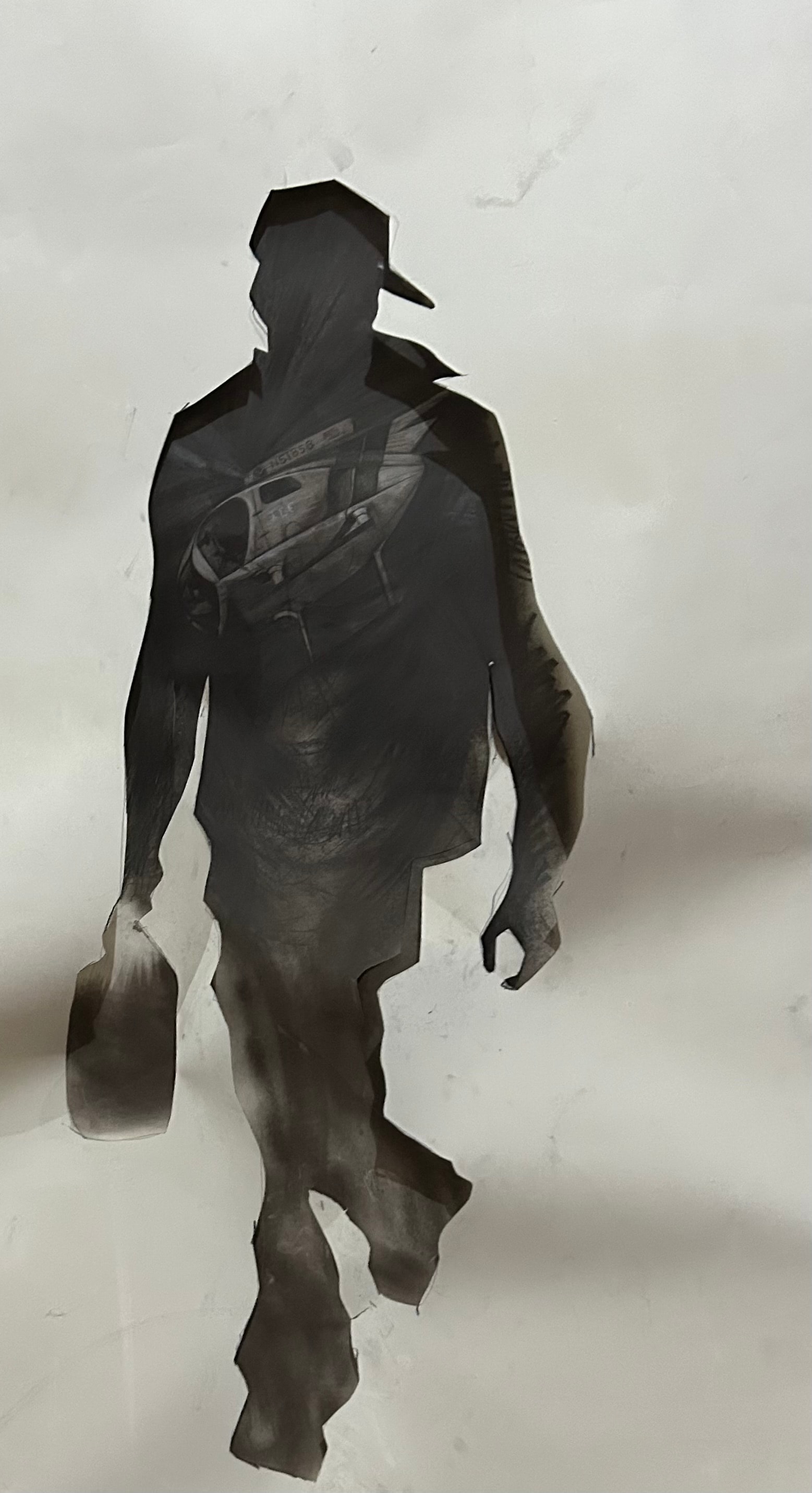 Hombre Cósmico: The ICE Helicopter Is Only a Deterrent — Ricardo Santos Hernández. Graphite sticks, graphite powder on Arches. Large-scale work. A monumental silhouette strides forward — hat low, bag in hand, the body of a man in motion. Inside that body, embedded in the graphite darkness of his chest, an ICE helicopter hovers. It does not stop him. It does not define him. It is only a deterrent — a machine of fear absorbed into the figure and carried forward, rendered powerless by the sheer force of the Hombre Cósmico's movement. The Arches paper holds the graphite like skin holds memory: layered, smudged, indelible. by Ricardo Santos Hernández