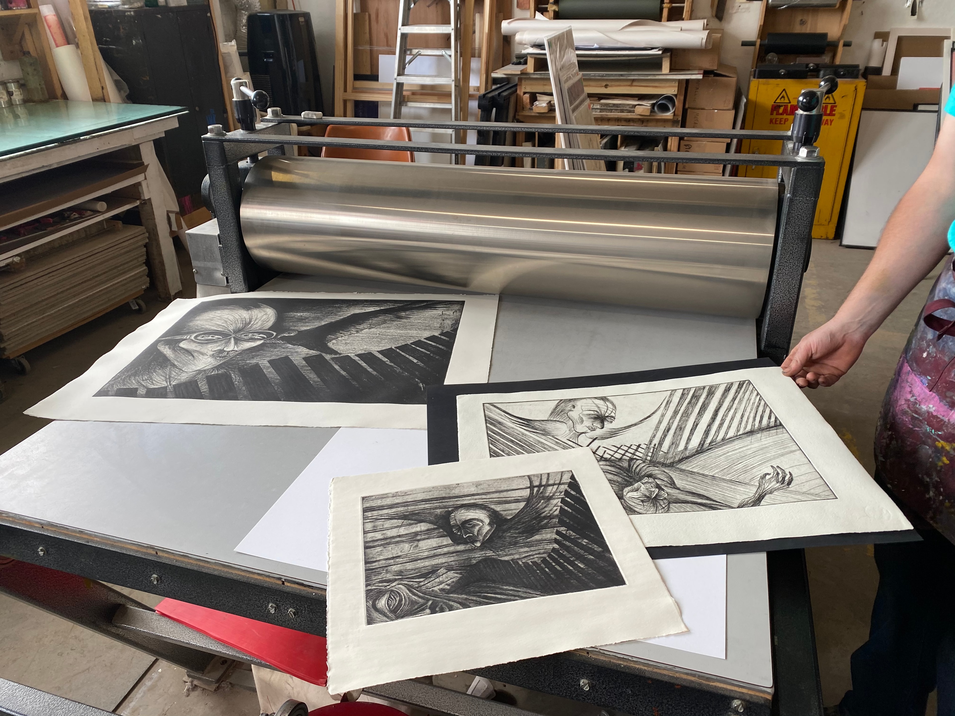 Hoof Print Chicago — Etchings and lithographs by Ricardo Santos Hernández fresh off the press at Hoof Print Chicago. Three prints laid out on the press bed — haunting figures with wings, angular shadows, and expressive line work. Printed with print master Gabe Hoar and Liz Borne. by Ricardo Santos Hernández