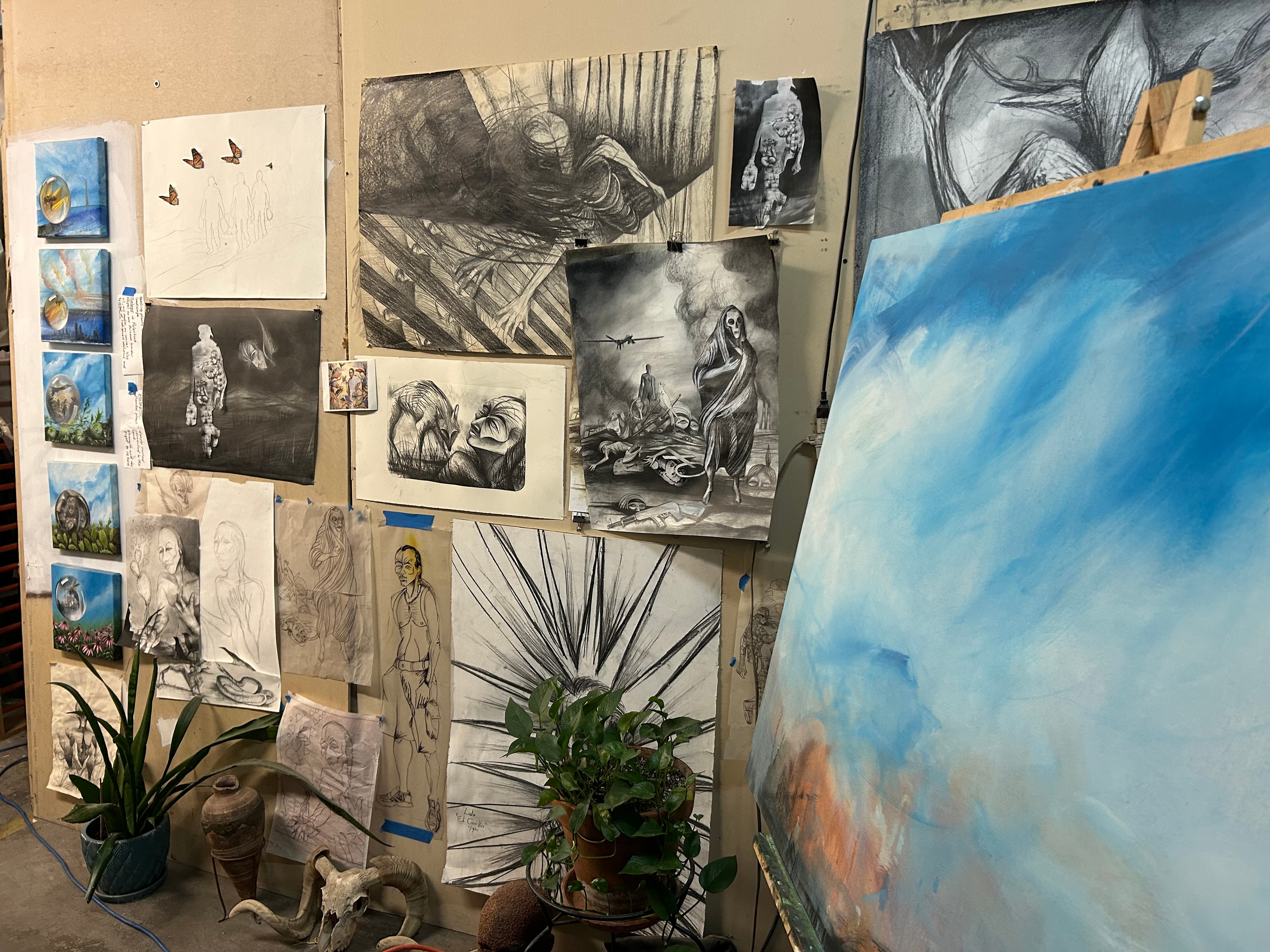 Works in Progress — The studio wall covered in drawings, sketches, and studies alongside a canvas in progress on the easel. A living archive of ideas, experiments, and evolving works that document Ricardo's creative process.