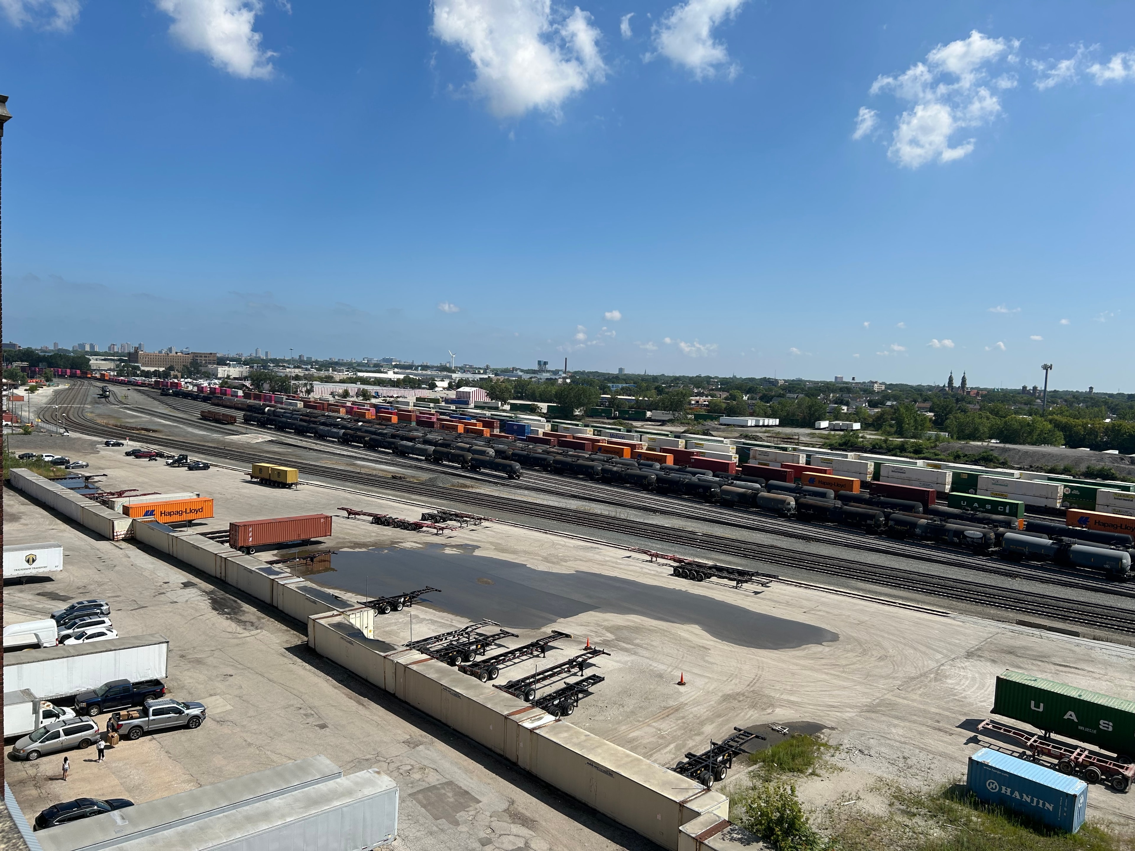 The Railway Hub — The view from Ricardo's studio window looking out over the largest North American railroad hub. Freight trains, shipping containers, and the vast industrial landscape stretch to the horizon — a daily panorama that has informed his work on urbanism, labor, and the movement of people and goods.