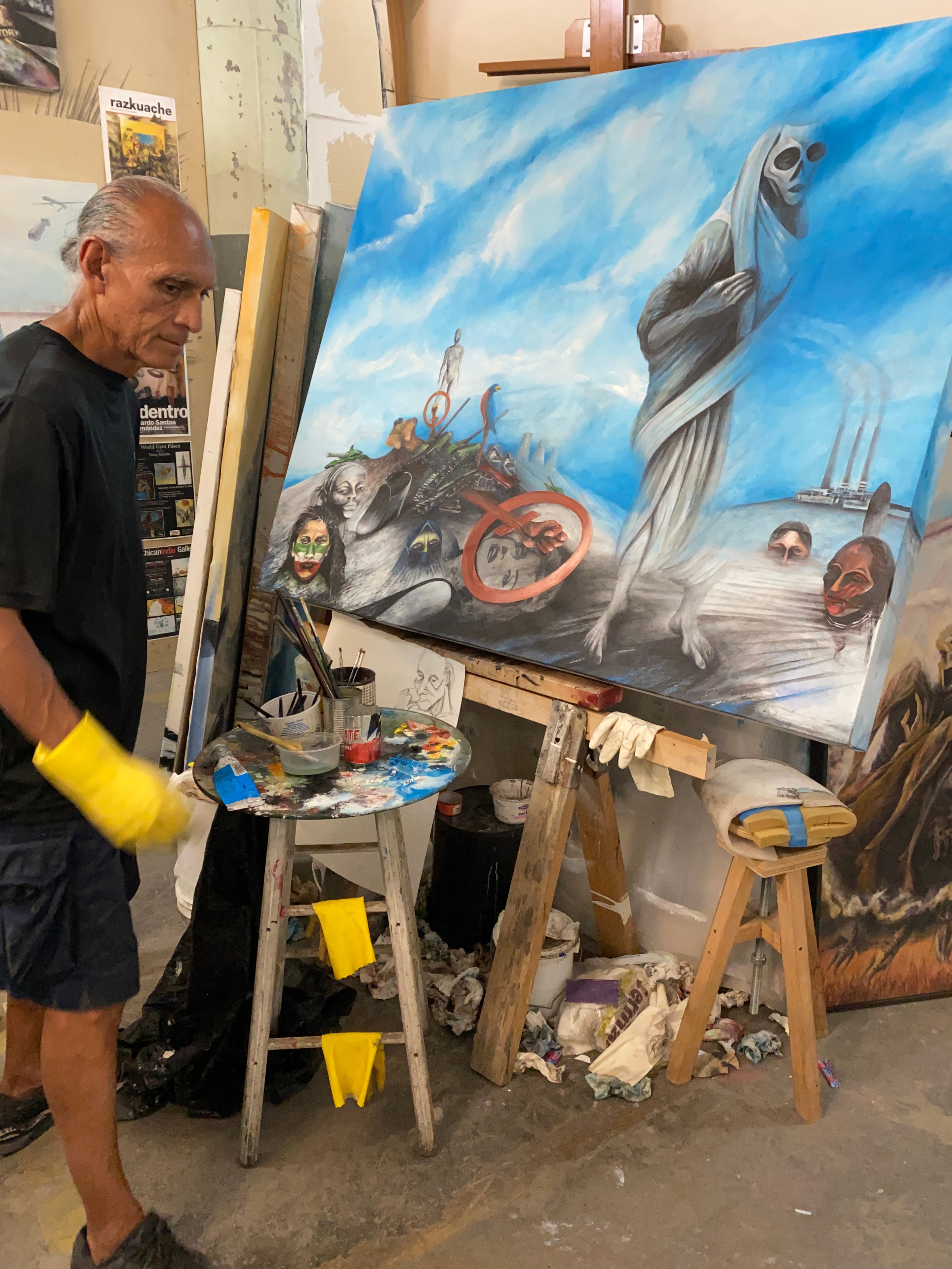 Ricardo at Work — The artist in his studio, palette in hand, a large canvas in progress behind him. A place of intense work, problem solving, and inspiration.